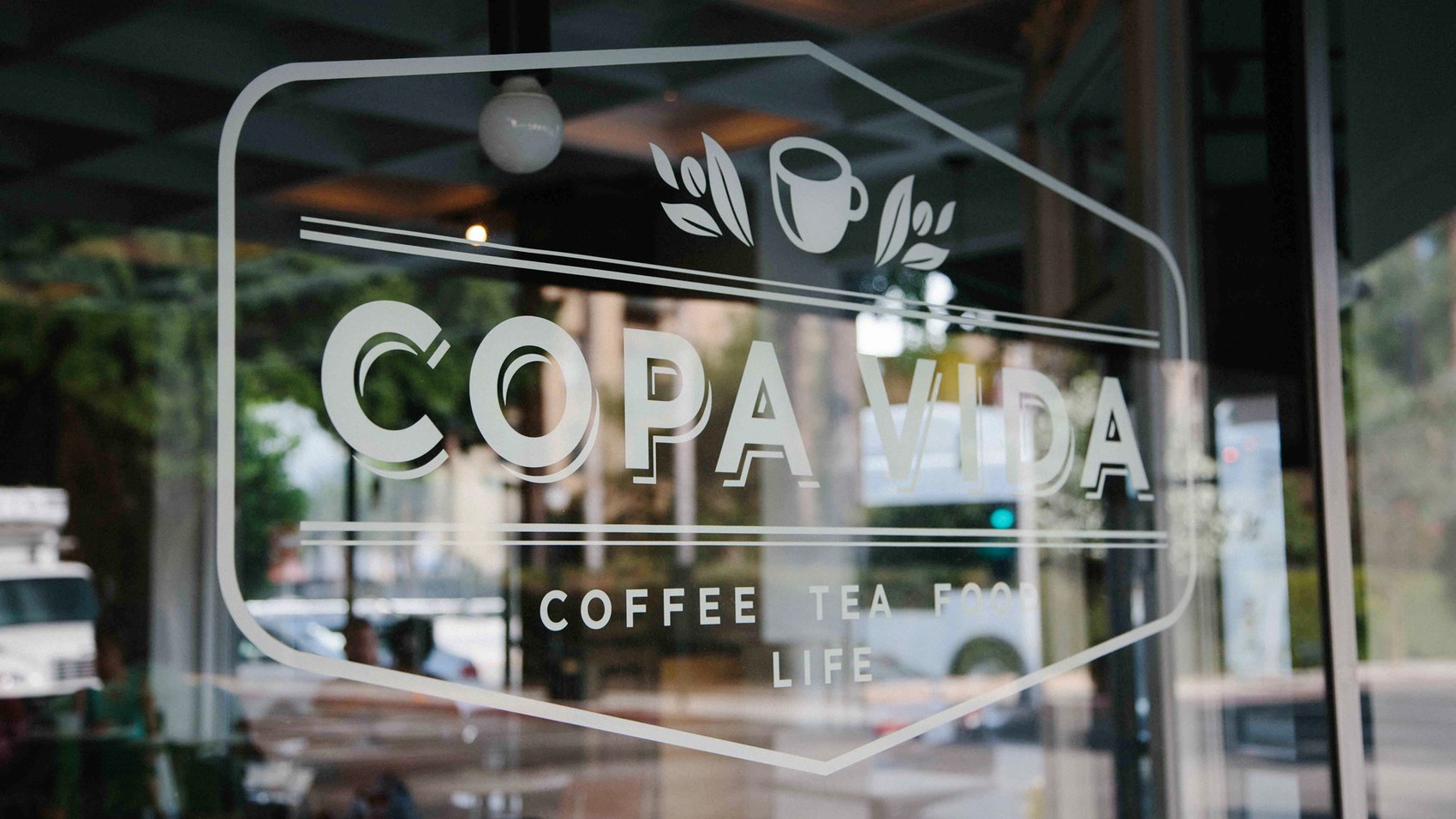 The etched Copa Vida logo on the storefront glass door